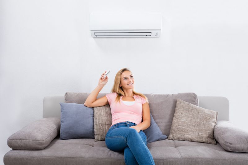Image of person sitting below a ductless system. Ductless ACs Improve Indoor Air Quality and Control Humidity.