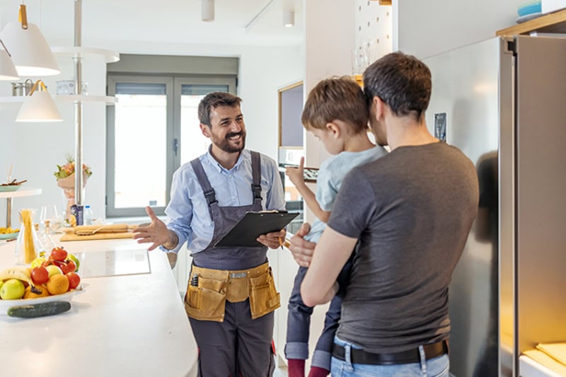 AC Maintenance Checklist. Professional plumber in uniform talking to male client and his small son indoors.