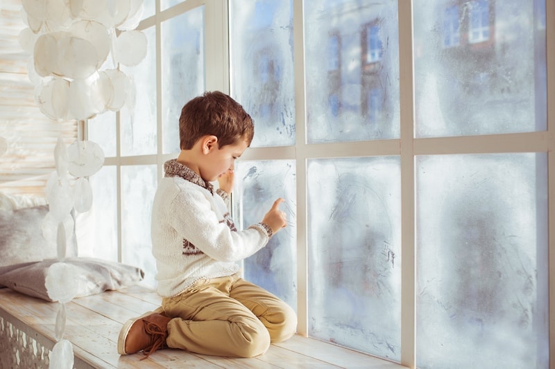 Little boy draws on a frozen window in the winter