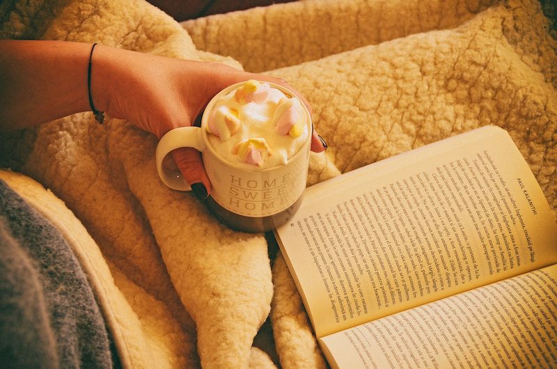 A person drinking hot chocolate and reading a book all about furnace filters in Fort Jennings